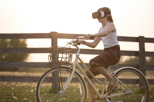Nainen pyöräilee virtuaalilasit päässään.