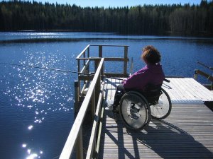 Nainen pyörätuolissa kalastamassa laiturilla